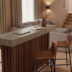 May include: A modern home bar with a concrete countertop and a dark wood slatted front. Two brown leather bar stools with black metal legs are in front of the bar. A laptop, notebook, and vase are on the bar.