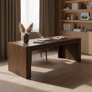 May include: A dark brown wooden desk with a fluted panel design on the legs and apron. The desk surface holds a brown vase with dried pampas grass, a closed notebook, a pair of glasses, a laptop, and an open book with a pen resting nearby.