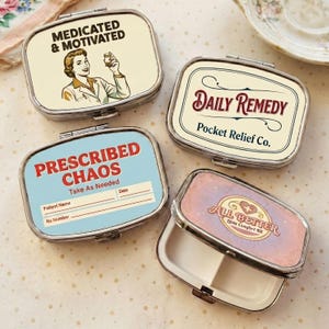 Pode incluir: Quatro caixas de comprimidos retangulares com molduras prateadas. Uma caixa diz "MEDICATED & MOTIVATED" com uma ilustração vintage. Outra diz "DAILY REMEDY Pocket Relief Co." A terceira diz "PRESCRIBED CHAOS" e a última "ALL BETTER Little Comfort Kit".