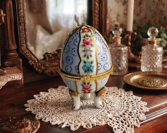 Uma pequena caixa de ovos de cerâmica para sua penteadeira, porta-anéis floral com detalhes dourados.