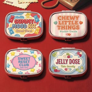 May include: Four rectangular metal pill cases with rounded corners. The top left features gummy bears and text GUMMY MOOD KIT Sweet Reset. The top right has pink stripes and text CHEWY LITTLE THINGS Pocket Treats. The bottom left has stars and text SWEET RESET CLUB Daily Carry. The bottom right has capsules and text JELLY DOSE Take Sweetly.