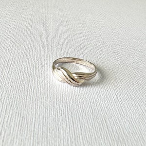 May include: A silver ring with a twisted design. The ring is smooth and shiny.