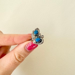 May include: A silver ring with two turquoise stones set in a decorative design.