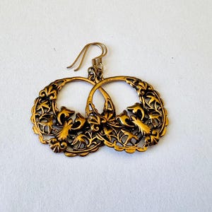 May include: Gold tone filigree earrings with a floral and bird design.