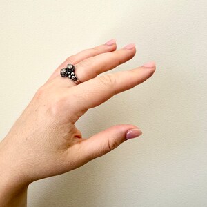 May include: A silver ring with two round stones and a beaded design.