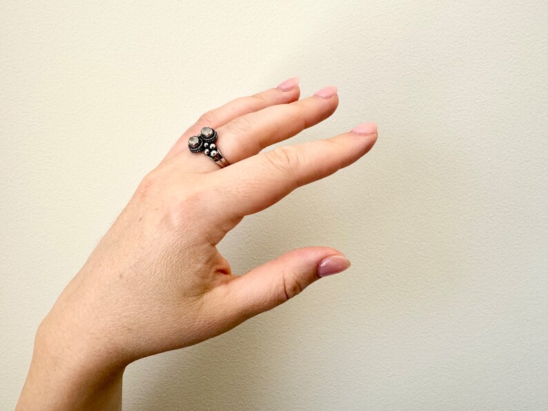 May include: A silver ring with two round stones and a beaded design.
