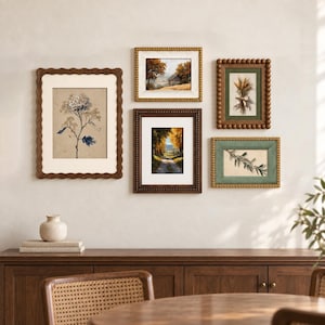 Puede incluir: Una composición de pared de galería con cinco obras de arte enmarcadas. La colección incluye un marco vertical grande con bordes ondulados, un marco horizontal, un marco con cuentas, un marco marrón oscuro y un marco verde con lámina botánica.