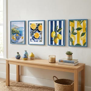 May include: Four framed art prints with blue beaded frames. The prints feature watercolor paintings of lemons and coastal scenes. A wooden bench below displays vases, a candle, books, and a small plant in a pot. A woven basket sits on the floor.