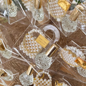 Detail view of empty refillable glass bottle and handwoven pearl keychain inside an acrylic gift box