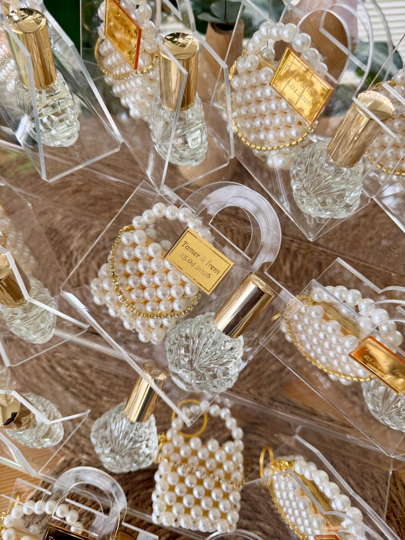 Detail view of empty refillable glass bottle and handwoven pearl keychain inside an acrylic gift box