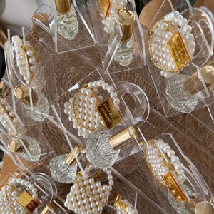 Bulk order of personalized luxury plexi purse favors with pearls and glass bottles for high-end events