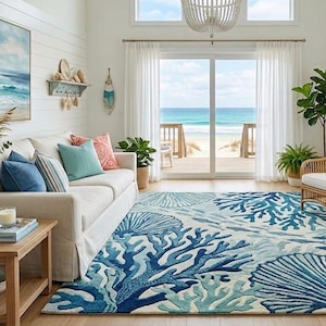 May include: A coastal-themed living room with a white sofa, blue and coral pillows, and a rug with a coral and seashell design. A painting of the ocean hangs above the sofa. Wicker chairs and a wooden coffee table complete the beachy decor.