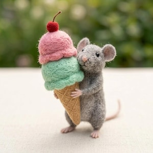 May include: A needle-felted gray mouse figurine standing upright and holding a large ice cream cone. The cone features a scoop of pink ice cream topped with a small red cherry, a scoop of mint green ice cream, and a textured tan waffle cone.