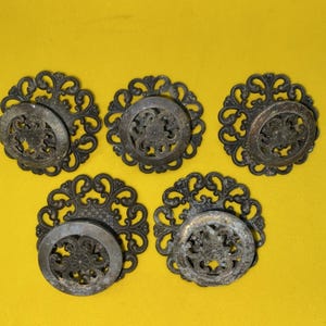 May include: Five circular metal drawer pulls featuring an intricate openwork filigree design with a dark, weathered finish. Each pull consists of a decorative outer ring and a central circular plate, showcasing a detailed floral-inspired pattern.