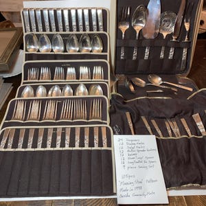 May include: A 105-piece silver-plated flatware set in the Morning Star pattern by Oneida Community Plate, dated 1948. The set includes spoons, forks, knives, and serving pieces organized in dark brown fabric cases with a handwritten inventory list.