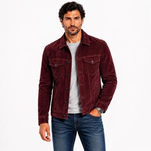 May include: A deep burgundy corduroy jacket featuring a classic collar, button-front closure, and two chest pockets with buttoned flaps. The jacket is worn over a plain light gray crew-neck t-shirt and paired with dark blue denim jeans.