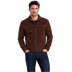 May include: A brown suede jacket with a collared neckline and a full-length zip. The jacket has a classic design with a tailored fit. The model is wearing dark blue jeans. A versatile outerwear piece.