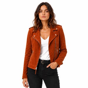 May include: A rust-colored suede jacket with a classic biker style. The jacket features a notched collar, asymmetrical zipper closure, and silver-tone hardware. The model is wearing a white V-neck shirt and black jeans. A belt with a silver buckle is visible.