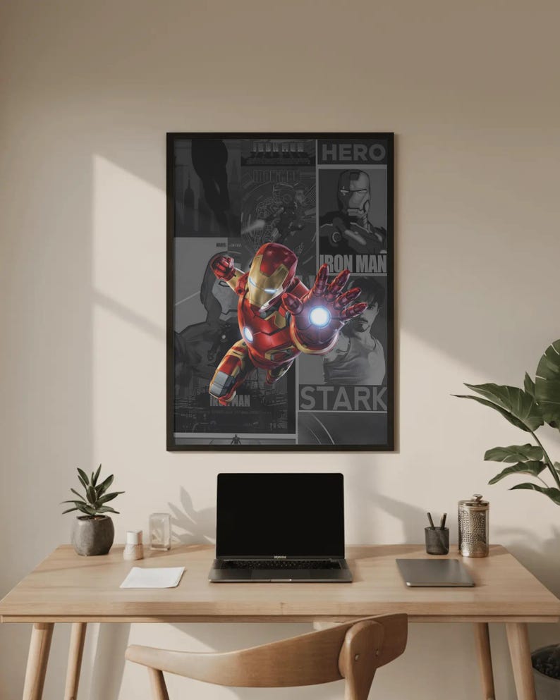 K&ouml;nnte beinhalten: Gerahmtes Iron Man-Poster mit dem Superhelden im Flug, mit einem rot-goldenen Anzug und einer leuchtenden Hand. Das Poster enth&auml;lt die W&ouml;rter "HERO", "IRON MAN" und "STARK". Das Poster wird &uuml;ber einem Holztisch mit einem Laptop und Zubeh&ouml;r angezeigt.