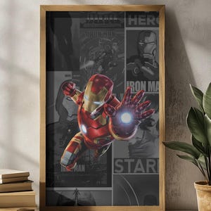 K&ouml;nnte beinhalten: Gerahmter Druck mit Iron Man in einer dynamischen Pose, in einem rot-goldenen Anzug und einer leuchtenden Hand. Der Hintergrund ist eine Collage aus grauen Comic-Panels mit den Worten "Iron Man" und "Star". Der Rahmen besteht aus hellbraunem Holz.