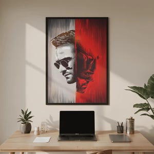 Peut inclure: Une affiche murale encadrée représentant un portrait divisé. Le côté gauche est en niveaux de gris, montrant un homme portant des lunettes rondes. Le côté droit est en rouge vif, représentant un personnage masqué aux traits anguleux et texturés.