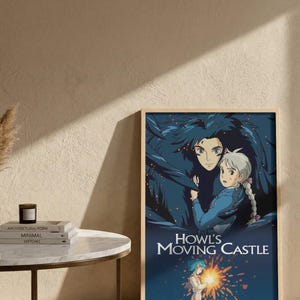 May include: A framed poster featuring artwork from "Howl's Moving Castle." The image depicts two characters with detailed facial features and flowing hair, set against a dark blue background. The title is prominently displayed in white text.