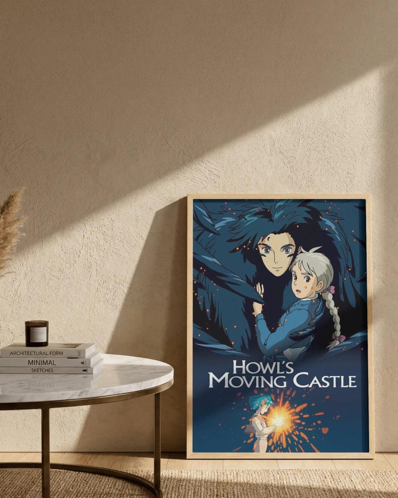 May include: A framed poster featuring artwork from "Howl's Moving Castle." The image depicts two characters with detailed facial features and flowing hair, set against a dark blue background. The title is prominently displayed in white text.