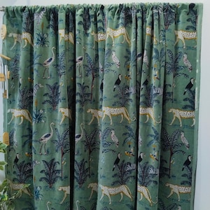 May include: Green curtain featuring a repeating pattern of leopards, birds, and palm trees. The design includes zebras, toucans, and other tropical elements. The fabric is a solid green colour.