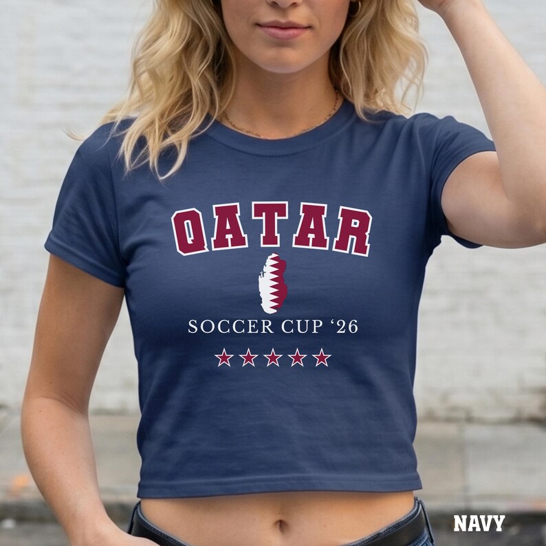 A navy colored baby tee featuring a Qatar map design with "Soccer Cup '26" and five stars.