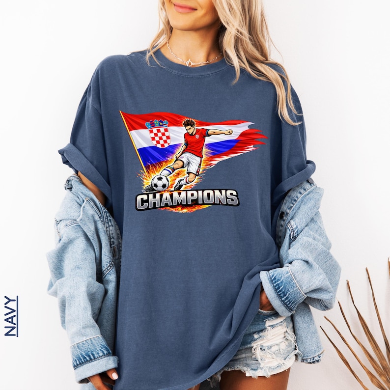 A woman wearing a navy t-shirt with a graphic of a soccer player and the text "CHAMPIONS" printed on it.