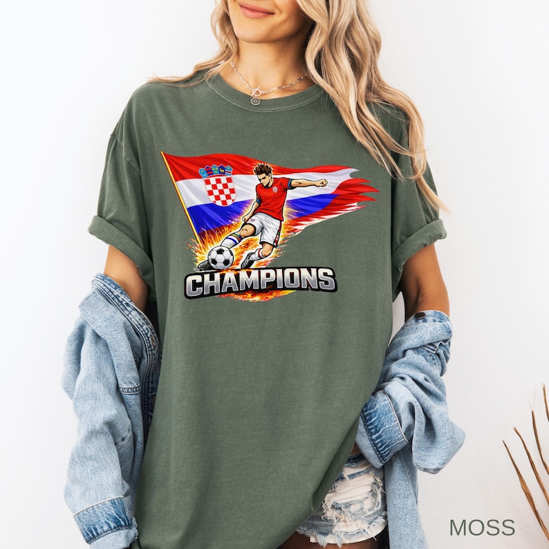 A woman wearing a moss t-shirt with a graphic of a soccer player and the word "CHAMPIONS" printed on it.