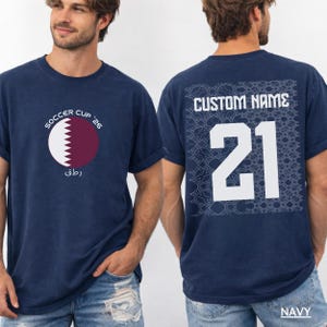 Two athletic men in a sports wearing custom NAVY oversized t-shirts showcasing the front Qatar emblem and the back personalized jersey number 21 design.