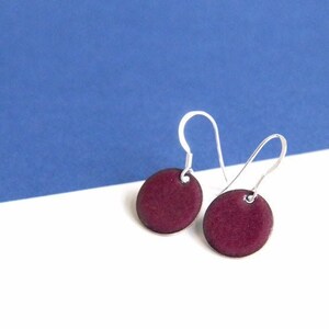 May include: A pair of silver dangle earrings with round, burgundy-coloured discs.