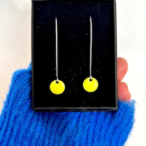 Può includere: Un paio di orecchini pendenti gialli con ganci d'argento in una scatola nera.