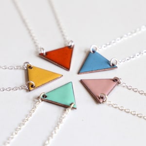 Puede incluir: Cinco collares de plata con colgantes triangulares en diferentes colores: naranja, amarillo, azul claro, rosa y verde claro.