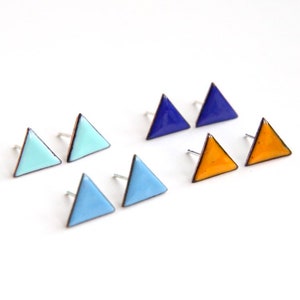 Puede incluir: Un conjunto de seis pendientes en forma de triángulo de esmalte azul, azul claro y amarillo. Los pendientes son pequeños y delicados, y serían un gran regalo para un amigo o un ser querido.