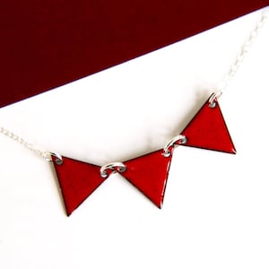 Può includere: Una collana a catena d'argento con tre ciondoli triangolari in smalto rosso.