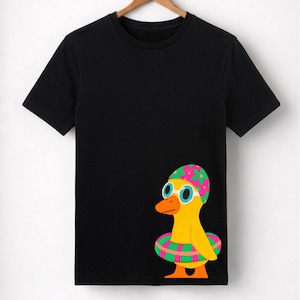 Puede incluir: Camiseta negra con un diseño de pato de dibujos animados. El pato amarillo con pico y patas naranjas lleva un gorro de baño, gafas y un flotador a rayas. El gorro de baño tiene detalles florales rosas y verdes.
