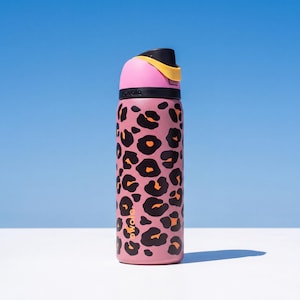May include: A pink water bottle featuring a black and orange leopard print design. The bottle has a black lid with a pink top and yellow accents. The brand name "gwala" is printed on the side.