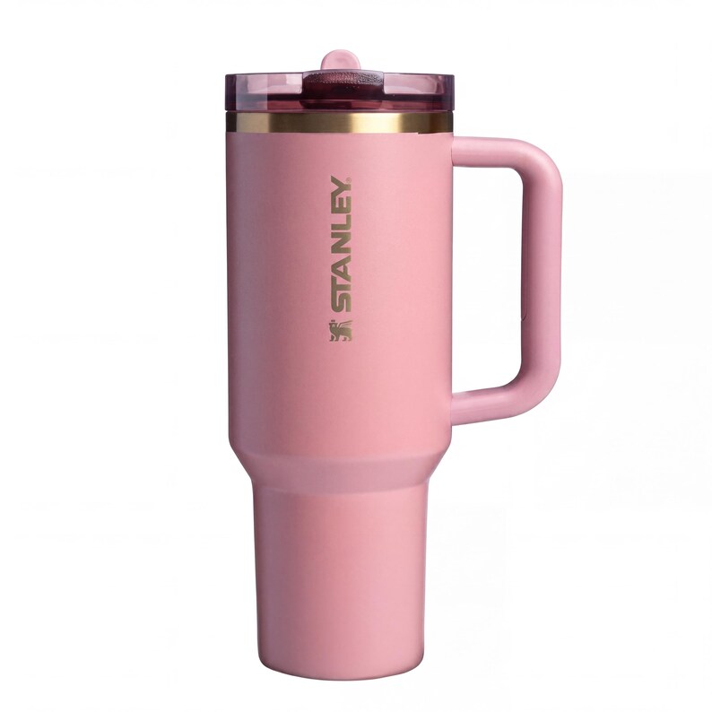 May include: A pink Stanley insulated tumbler with a handle and a clear lid. The tumbler has the Stanley logo printed on the side. The tumbler is designed to keep beverages hot or cold for hours.
