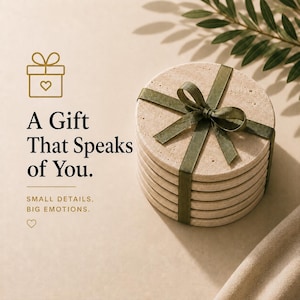 May include: A stack of round, beige stone coasters tied with a green ribbon. The image includes the text "A Gift That Speaks of You" and "Small Details, Big Emotions."