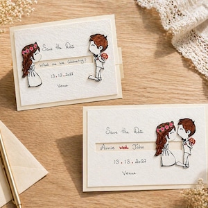 Op de afbeelding: Twee trouwkaarten "Save the Date" met cartoon illustraties van een stel. De kaarten hebben de tekst "Save the Date", "What are we Celebrating?" en de datum "13.13.2027". De kaarten liggen op een houten oppervlak.