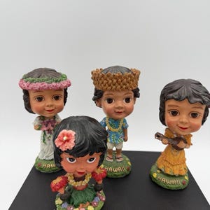 May include: A set of three ceramic mugs with a speckled, cream-colored glaze. Each mug features a different hand-painted design: a blue and green leaf, a yellow flower, and a red berry. The mugs have a simple, rounded shape.