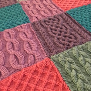 Peut inclure: Une couverture tricot&eacute;e color&eacute;e avec diff&eacute;rents motifs et textures. La couverture est faite de diff&eacute;rentes nuances de rose, violet, vert et bleu.