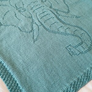 Pode incluir: Um cobertor de beb&eacute; em tric&ocirc; azul claro com um desenho de elefante.