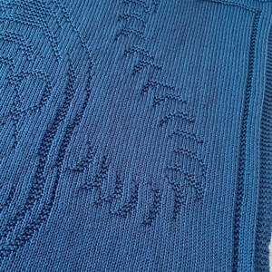 Pode incluir: Um cobertor de beb&eacute; azul de malha com um padr&atilde;o texturizado.