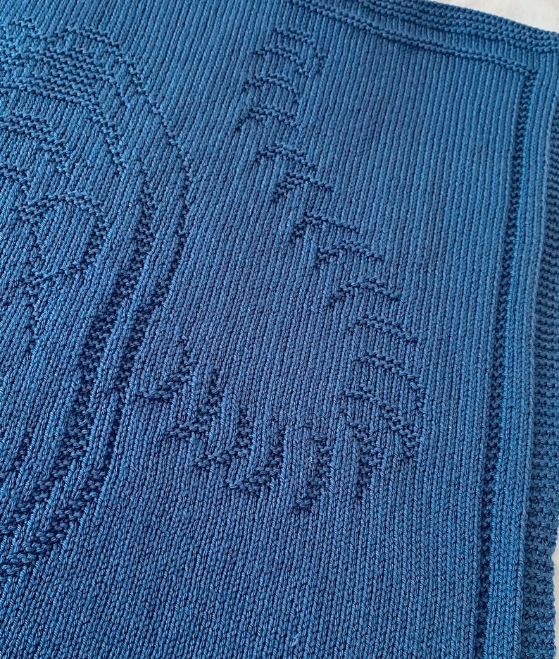 Pode incluir: Um cobertor de beb&eacute; azul de malha com um padr&atilde;o texturizado.
