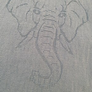 Pode incluir: Um cobertor de malha verde com um design de elefante.