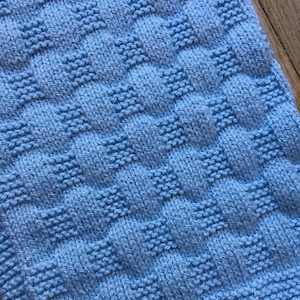 Può includere: Una copertina per neonati di colore azzurro chiaro con un motivo a trama.