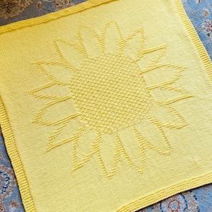 Könnte beinhalten: Eine gelbe gestrickte Babydecke mit einem Sonnenblumenmuster.